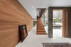 A modern residential interior featuring wooden stairs and a concrete column.