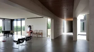 Contemporary living room with concrete walls and wooden ceiling beams.