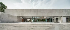 Modern, minimalist house with concrete exterior and large windows.