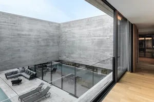 A modern residential interior with concrete walls and glass elements.