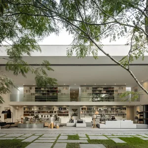 A modern living room with concrete surfaces, minimalist furniture, and extensive bookshelves.