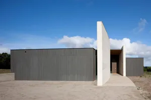 A modern residential home featuring a minimalist design with a concrete exterior and metal structural elements.