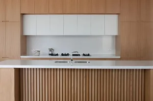 Modern, minimalist kitchen with white and wooden accents, featuring a white countertop and wood-paneled island.