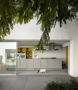 A modern minimalist kitchen with a white color scheme and yellow accents, featuring white cabinets, a white countertop, and a