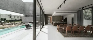 Modern residential interior featuring a concrete dining area with glass and steel accents and a backyard pool.