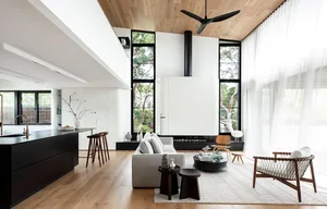 Modern minimalist living room with large windows, white walls, and wood flooring.