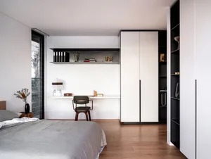 A contemporary bedroom with modern minimalist design, featuring wooden flooring, a stylish chair, and organized furniture.