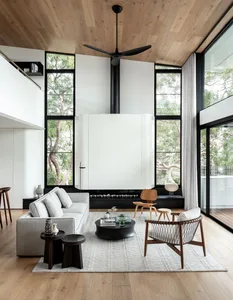 A modern minimalist living room featuring wood, glass, and metal elements.