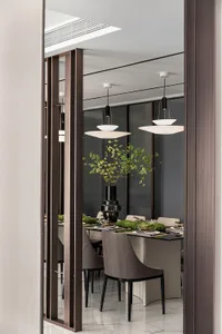 A modern dining room featuring metallic chairs, glass tabletop, and minimalist decor.