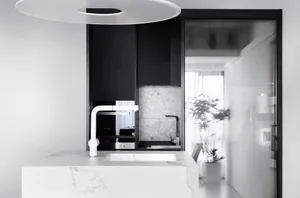 Modern kitchen with black cabinets, white marble countertops, and minimalist design