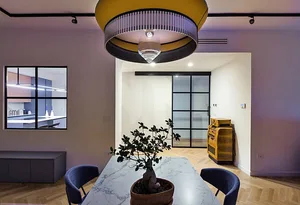 A modern dining room featuring a marble table with a bonsai plant, blue chairs, and a minimalist design.
