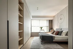 A modern minimalist bedroom featuring neutral tones and a tidy, organized space.