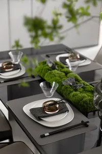 Modern table setting with plates, glasses, and chopsticks on a glass surface.