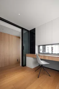 Modern, minimalist workstation with sleek, white chair and wood and glass surfaces.