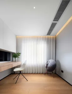 Modern minimalist home office featuring a sleek desk, white chair, white curtains, and a hanging air diffuser.