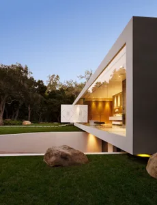 Modern minimalist house with large glass windows and a sleek exterior design.