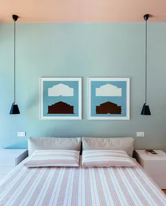 A modern bedroom with a bed, striped bedding, and two blue-framed pictures on the wall.