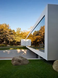 Modern exterior of a building featuring a glass facade, concrete walls, and large stone elements.