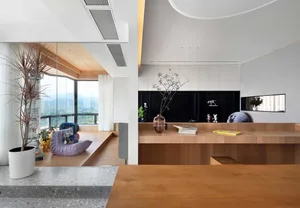 Modern living room with wooden furniture, glass wall, concrete floor, and potted plants.
