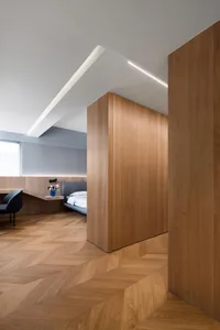 Modern minimalist bedroom featuring a wooden floor with a herringbone pattern.