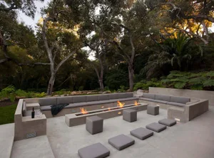 A modern outdoor lounge area with a fire pit and seating.