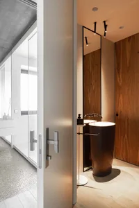 A modern bathroom featuring wood accents, light flooring, and metal fixtures.