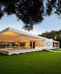 Modern house with white exterior cladding and large windows under a clear sky.