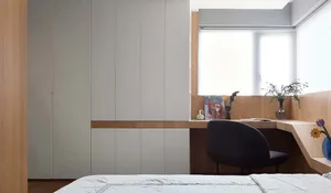 A minimalist bedroom featuring a bed, a desk with a chair, a window, and wood-paneled walls and cabinets.