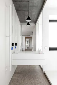 Minimalist modern bathroom with white walls, concrete ceiling, and white floating vanity.