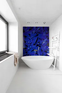 Modern bathroom with blue mosaic accent wall and white freestanding tub.