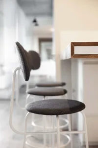 Modern kitchen with white counter stools and textured fabric seats.