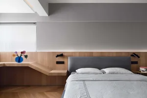 Minimalist bedroom with wooden furniture, grey headboard, and grey bedding