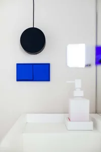 Modern minimalist bathroom with plastic fixtures and blue accents.