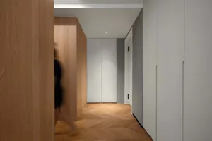 A modern minimalist hallway featuring wooden walls and concrete flooring with a person walking.