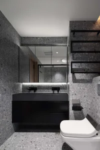 A modern bathroom with a terrazzo countertop, black vanity, and black mirror with hidden lighting.
