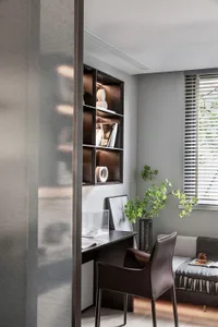 Modern, organized office space featuring a wooden shelf with glass vases, a leather chair, and a small green plant.