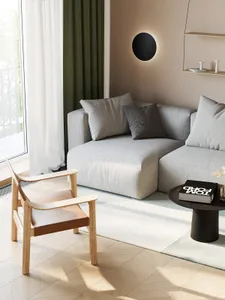 Modern living room with a light-colored fabric sofa, wooden armchair, and black coffee table.