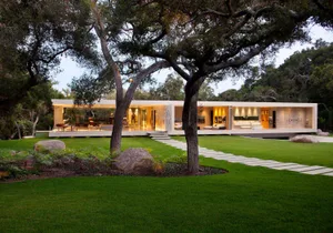 Modern residential home with extensive glass walls and sleek steel accents.