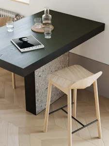 A modern coffee table with a terrazzo top and wooden base, featuring transparent glasses and a magazine on the table.
