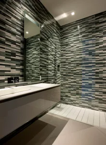 Modern minimalist bathroom with glass tile flooring, a floating vanity, and a walk-in shower.