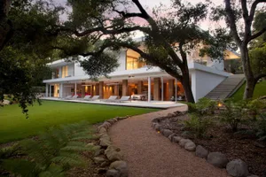 A modern residential house with a glass exterior and a spacious patio.