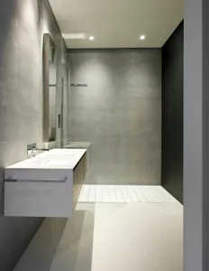 Modern minimalist bathroom with concrete walls and floor, featuring a floating vanity sink and a large mirror.