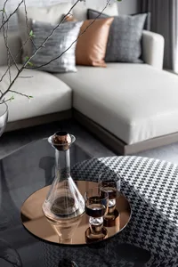 Modern minimalist living room with glass vase and two glasses on a metallic table.