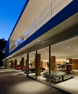 A modern car showroom with glass walls displaying various cars.