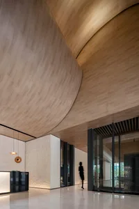 A modern hotel lobby featuring a wooden archway and marble flooring.