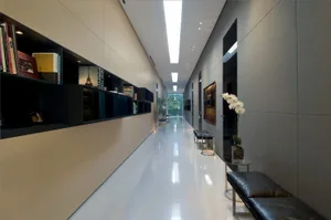 Long, sleek, modern interior corridor with concrete walls and a reflective floor.