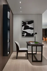 A modern industrial home office with a wooden desk and chair, a black and white abstract painting, and a built-in floating sh