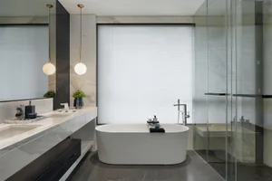 A modern bathroom with a white bathtub, marble countertops, and glass shower enclosure.