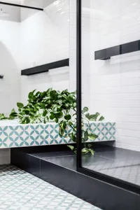 A modern bathroom featuring patterned ceramic tiles and glass fixtures.