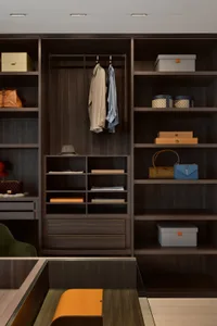 A modern closet with dark wooden shelves and drawers, featuring organized storage and clothing items.